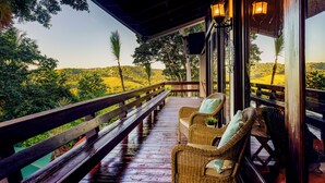 A wooden deck with wicker furniture and a view of a lush landscape. - Green Nest at the Hills (Guaynabo)