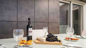 A table set with a bottle of wine, glasses, a wooden board with cheese and grapes, and plates with pastries.