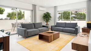 A modern living room with two grey sofas, a wooden coffee table, and a yellow rug.