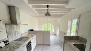 Cocina amplia con armarios blancos, encimeras de granito y una isla central.