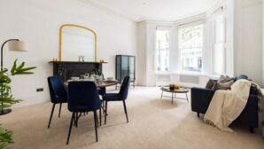 Een woonkamer met een open haard, een eethoek en een bank.