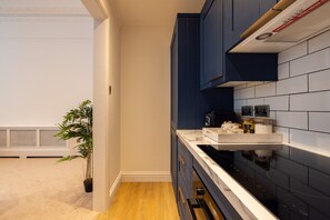 A modern kitchen with dark blue cabinets, a white countertop, and a black stove. - Luxury 2-bed Apartment in Knightsbridge (London)
