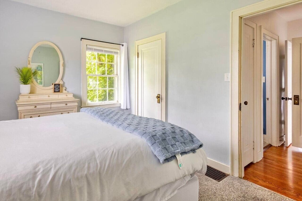 Une chambre à coucher avec un lit, une commode, un miroir et une fenêtre.