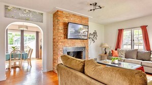 A living room with a brick fireplace, a television mounted above it, and a sofa. - Large House w/King Bed, Parking, Deck, Restaurants (Indianapolis)