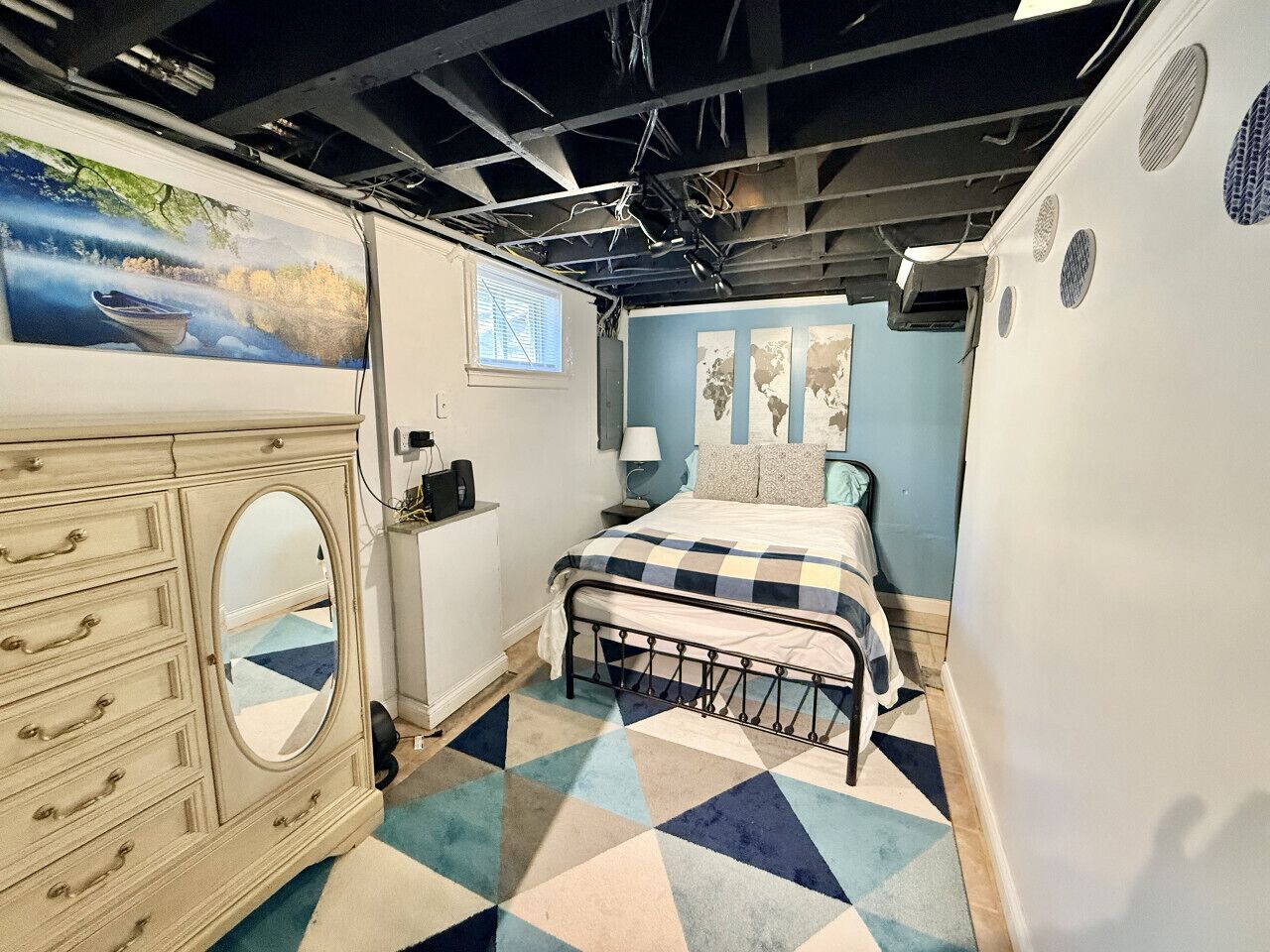 Une chambre à coucher avec un lit, une commode et un mur orné d’un tableau.