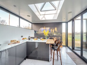 A modern kitchen with a skylight, a dining area with bar stools, and a mural of a castle. - 3 bedroom accommodation in Bryn Pydew, near Llandudno (Bryn Pydew, near Llandudno)