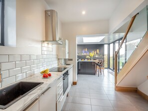 Una cocina moderna con una isla grande, horno empotrado y vistas a un castillo a través del muro de cristal.