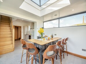 Una cocina moderna con tragaluz, escalera de madera y un comedor con taburetes de bar.