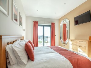 A bedroom with a bed, a dresser, a TV, and a large window with curtains. - 3 bedroom accommodation in Bryn Pydew, near Llandudno (Bryn Pydew, near Llandudno)