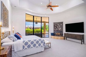 Une chambre moderne avec un lit, une télévision, une cheminée et une vue sur la verdure.