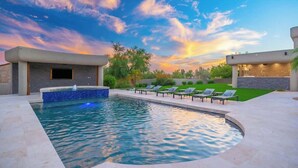Piscina com espreguiçadeiras, hidromassagem e vista para o pôr do sol.