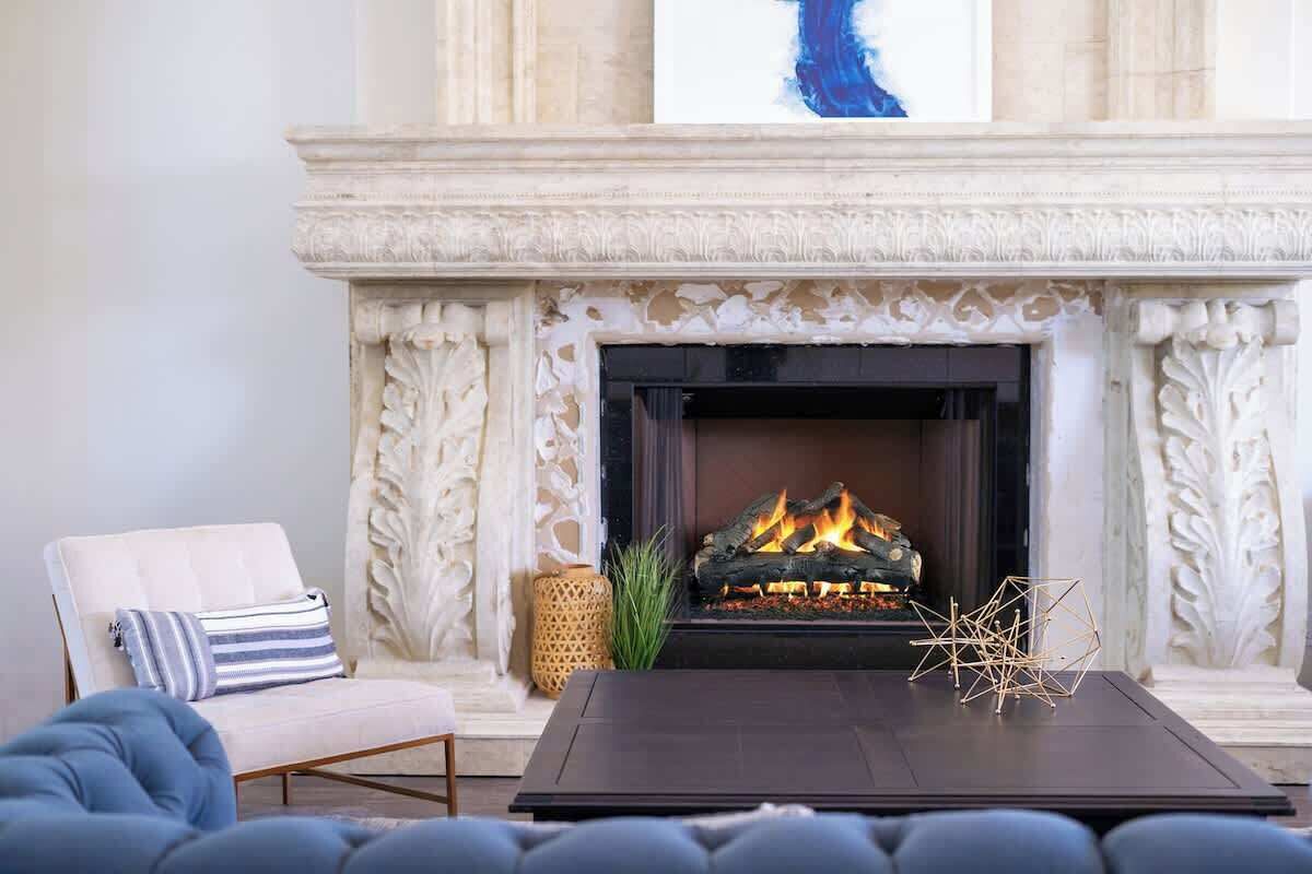 Une cheminée au design moderne, un canapé agrémenté d’un coussin à rayures et une table décorative placée devant.
