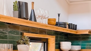 A kitchen with wooden shelves, a sink, and various kitchen items.