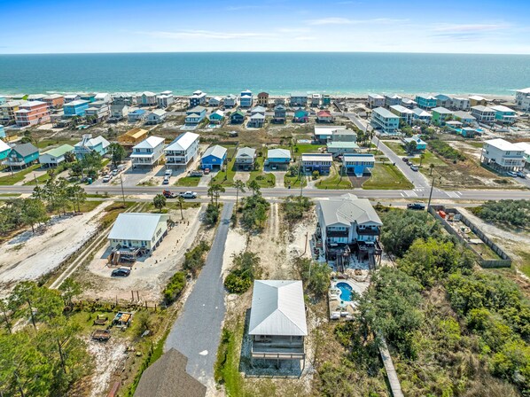 An aerial view of a coastal residential area with houses, roads, and a beach.
