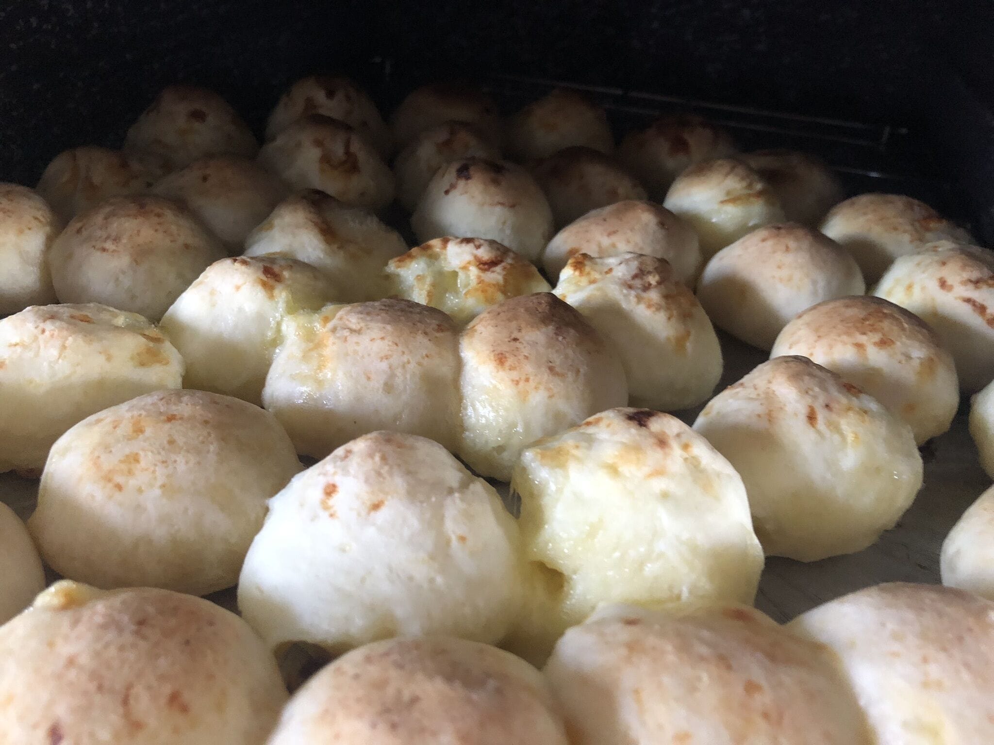 A close-up of round, golden-brown baked goods in a baking tray.