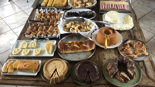 Une table de buffet proposant une variété d’aliments, notamment des pâtisseries, du pain, des fromages et des fruits.