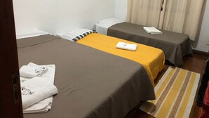 Une chambre d’hôtel avec deux lits, chacun recouvert d’une couverture marron et agrémenté d’un tapis à rayures jaunes.