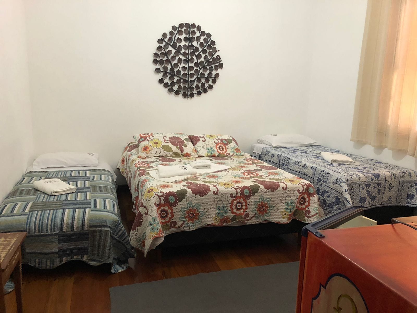 A room with two single beds, a decorative wall piece, and a wooden floor.