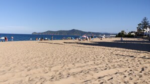 A sandy beach with umbrellas and people.