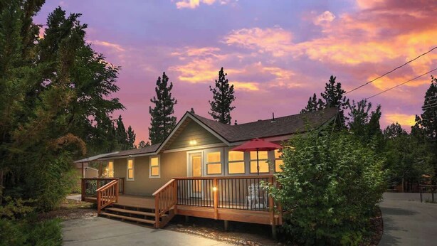 A two-story house with a wooden deck, a front porch, and a garage. - Bearpaw Bungalow | Fenced Yard · Near Lake (Big Bear Lake)