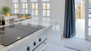 A modern kitchen with a large island, white cabinetry, and a view of the backyard through large windows.