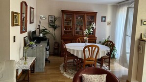 Un coin repas comprenant une table ronde, des chaises, un buffet et un bureau avec un ordinateur.