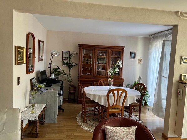 A dining area with a round table, chairs, a cabinet, and a desk with a computer.