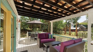 A covered outdoor patio with wicker furniture and a table under a pergola. - Folly Vacation 305 Beach Home (Folly Beach)