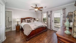 A bedroom with a wooden bed, a ceiling fan, a nightstand with a lamp, and a view through a glass door. - Relaxing getaway at Honey's Condo (Hot Springs)