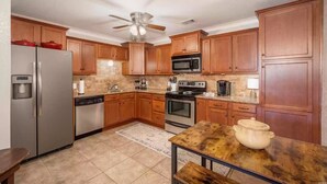 A kitchen with wooden cabinets, stainless steel appliances, and a ceiling fan. - Relaxing getaway at Honey's Condo (Hot Springs)