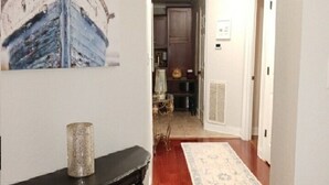 A hallway with a wooden floor, a black console table, and a painting of a boat. - Relaxing getaway at Honey's Condo (Hot Springs)
