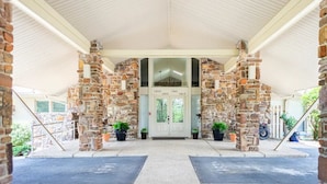 A covered entrance with stone pillars, a double door, and potted plants. - Relaxing getaway at Honey's Condo (Hot Springs)