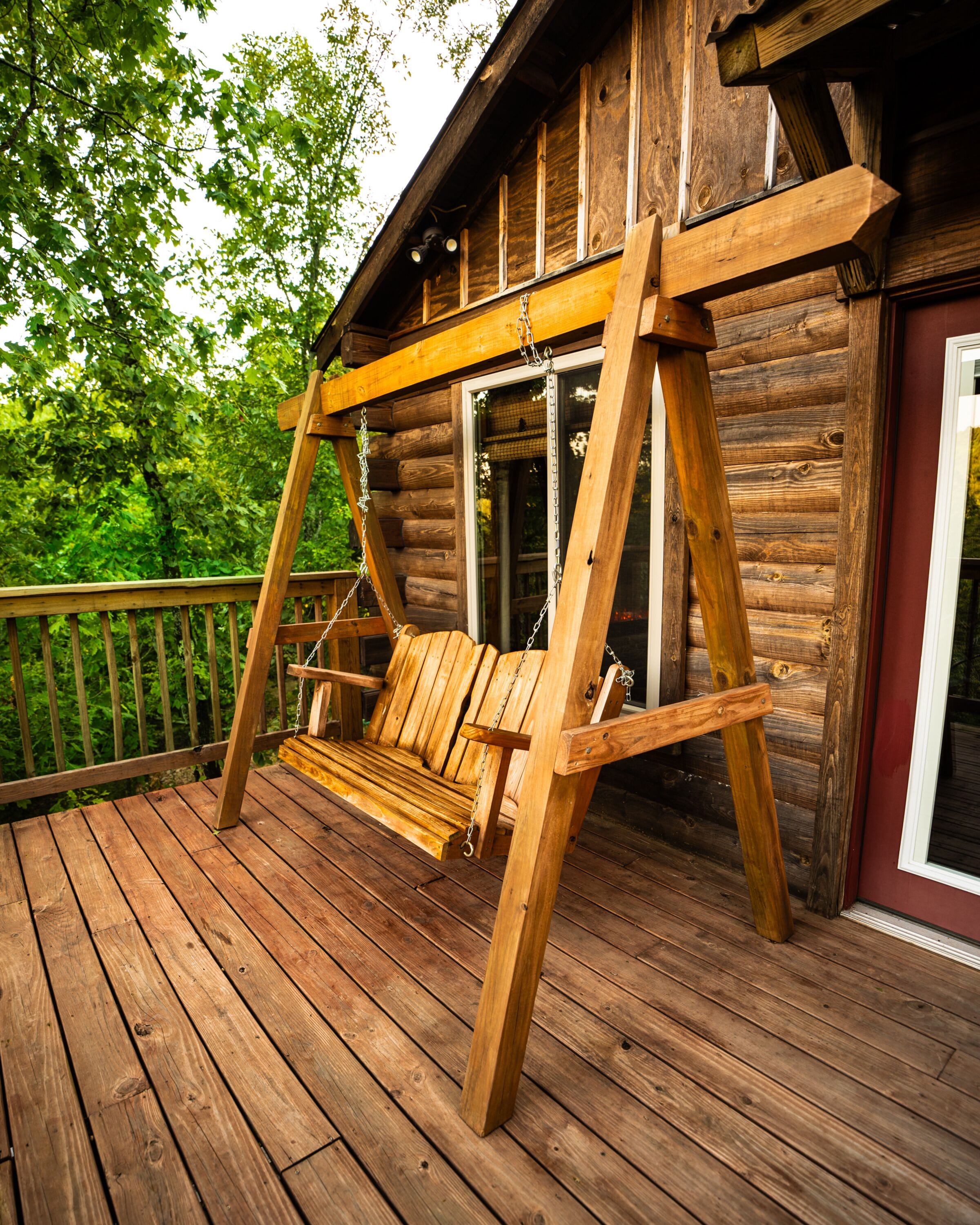 A wooden deck with a swing chair.