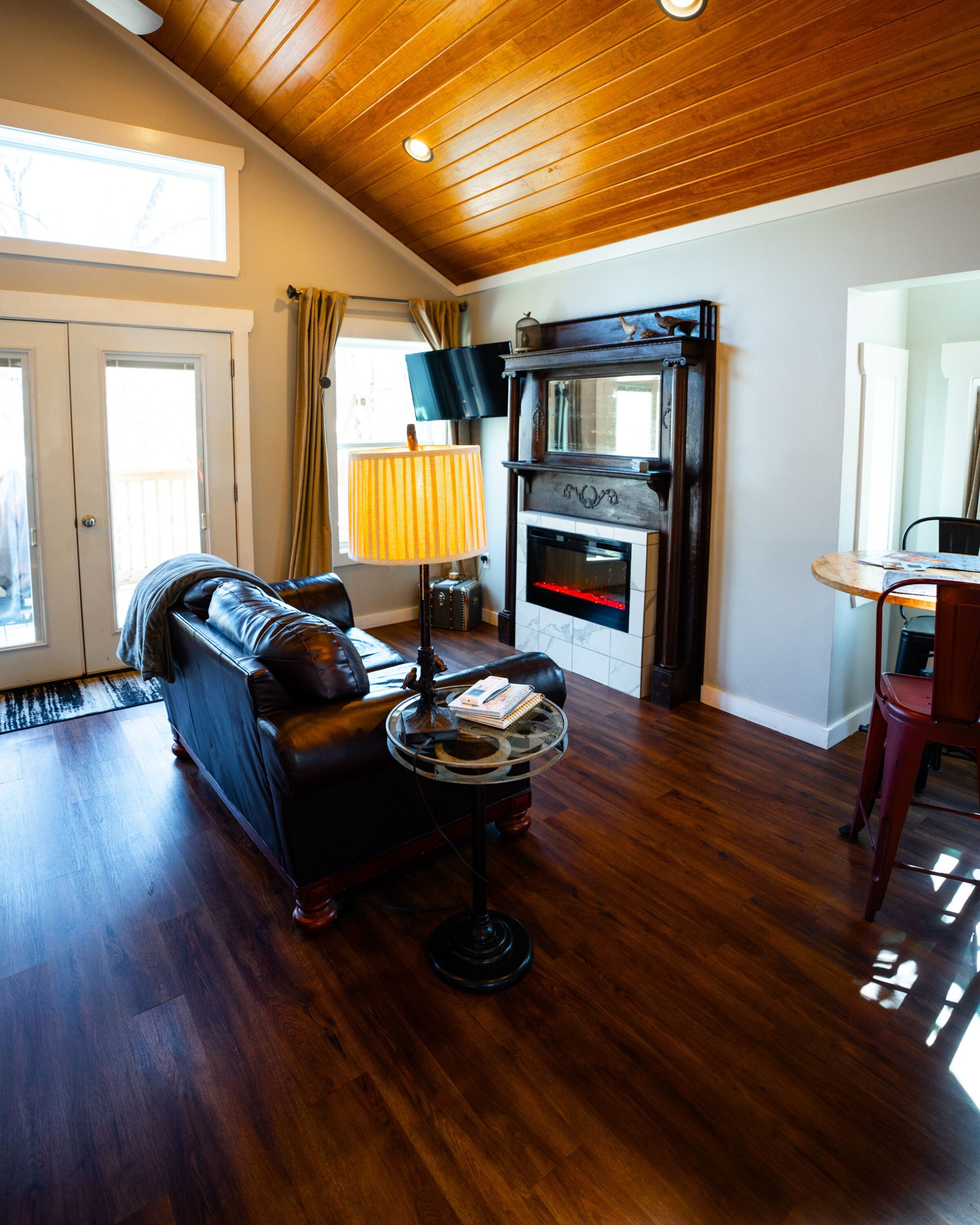 A living room with a fireplace, leather sofa, and a coffee table with books and a lamp.
