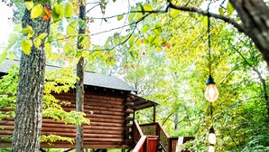 A wooden cabin with a wooden deck and a hanging light fixture. - Starlight Haven Hot Springs (Hot Springs)