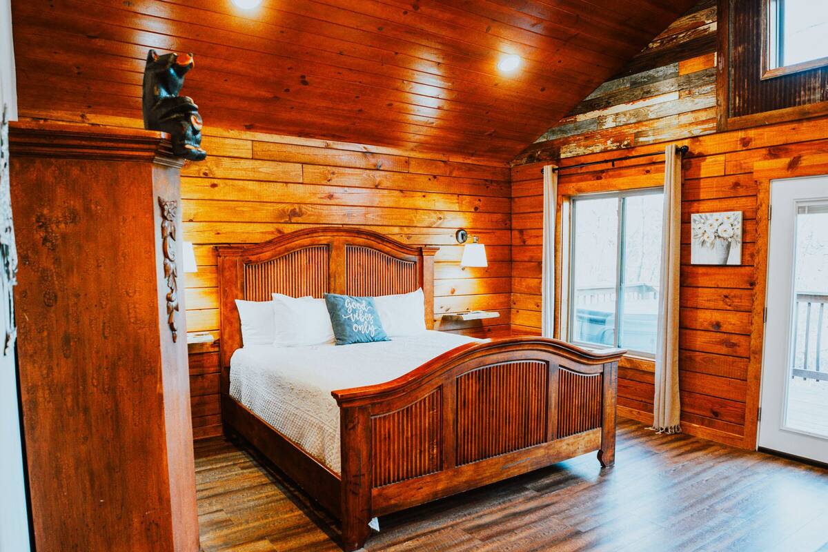 A wooden-paneled bedroom with a bed, a nightstand, and a dresser.