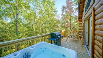 A wooden deck with a hot tub, a grill, and a ladder.