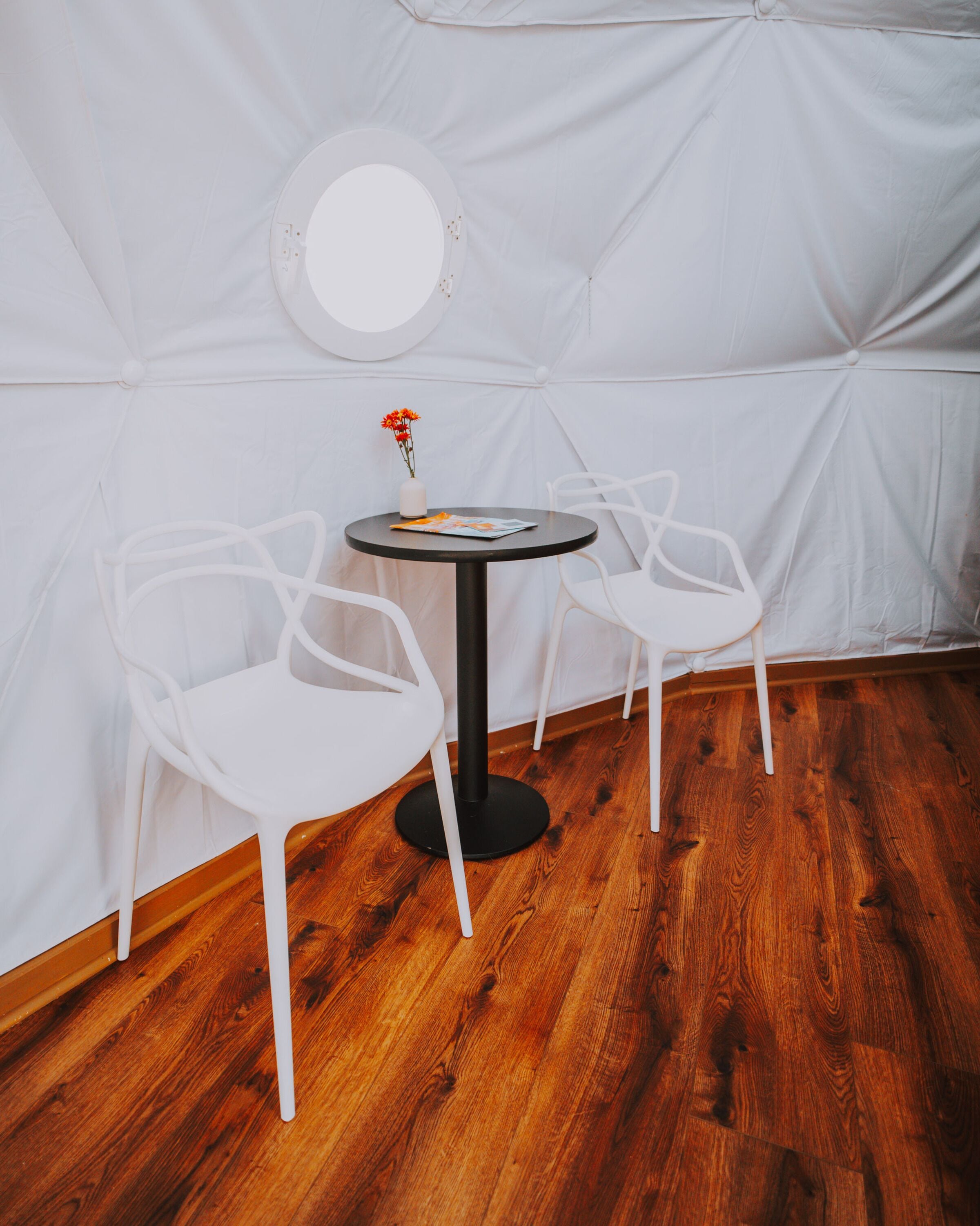 A white tent-like room with a round table and two white chairs.