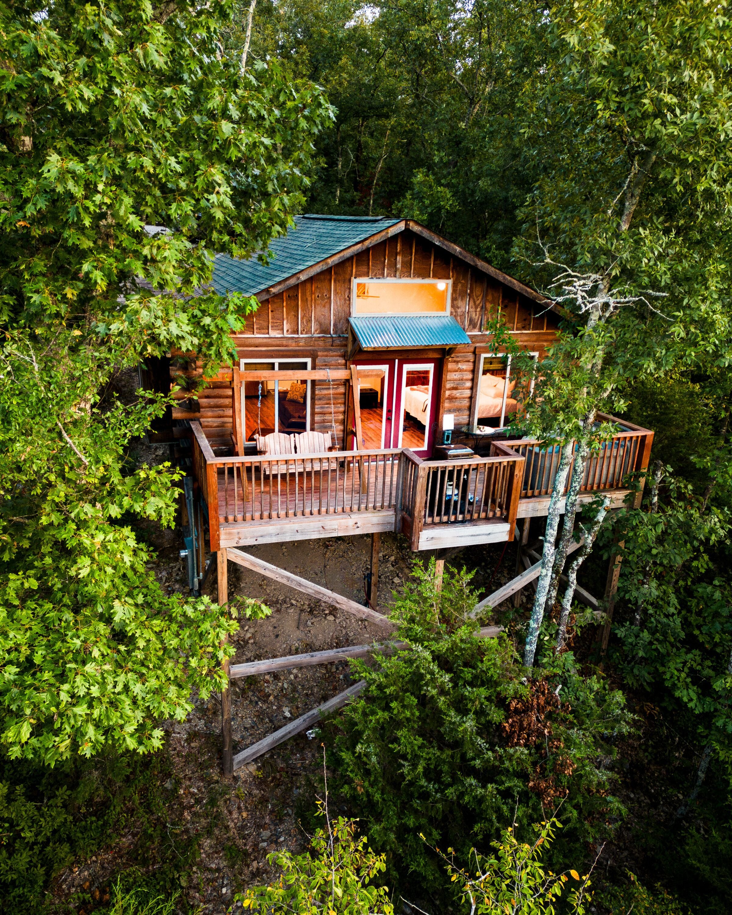 A cabin with a deck, surrounded by dense forest.