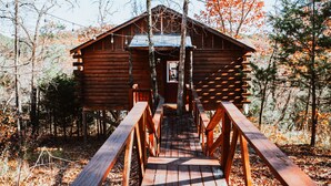 A wooden log cabin with a wooden deck leading to the entrance. - Starlight Haven Hot Springs (Hot Springs)