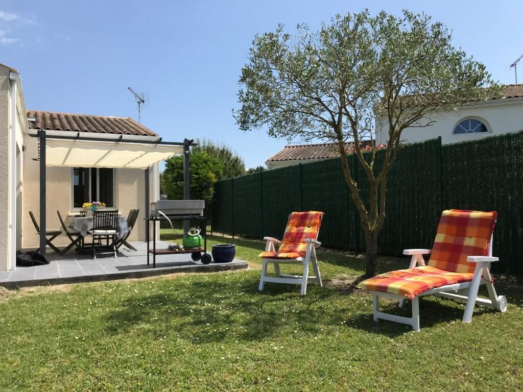 An outdoor patio area with a table and chairs, a barbecue grill, and two lounge chairs.