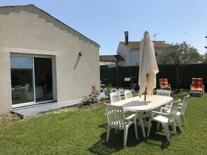 A house with a patio area featuring a table and chairs, a sliding glass door, and a covered umbrella.