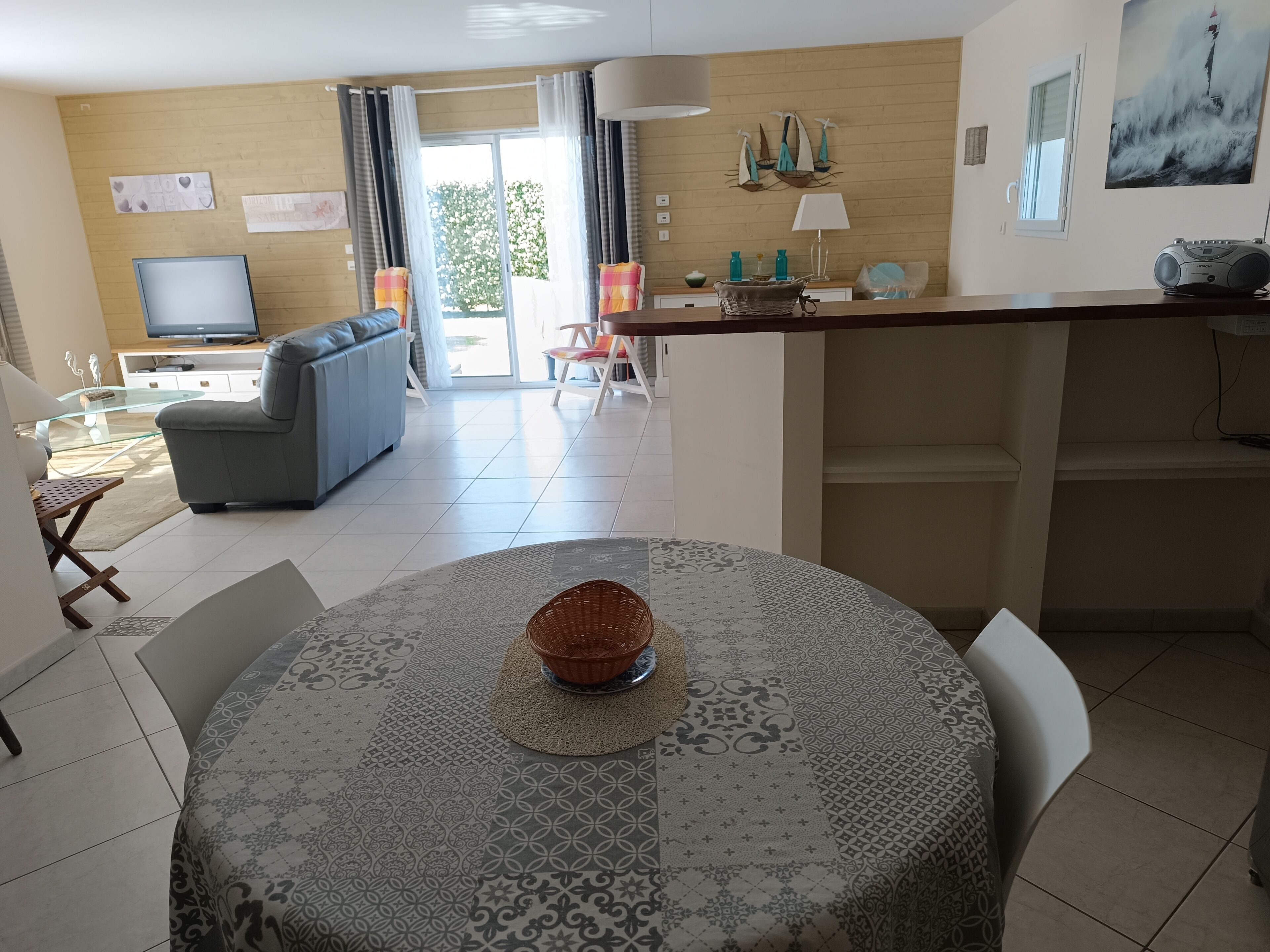 A modern living room with a sofa, a television, and a dining area with a table and chairs.