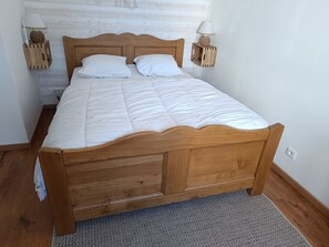 A wooden bed with white bedding, two bedside lamps, and a textured rug. - Beautiful house near the ocean—quiet, charming, and perfect for a family vacation (Meschers-sur-Gironde)