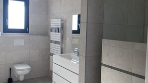 Ein modernes Badezimmer mit Toilette, Waschbecken und Spiegel.