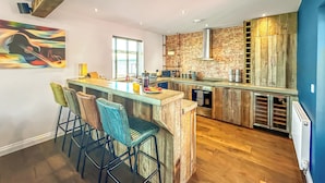 A modern kitchen with a central island, bar stools, and a brick accent wall.