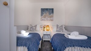 A hotel room with two beds, a nightstand with a lamp, and a painting on the wall. - Salty Dog Apartment @ Sunnybeach (Paignton)