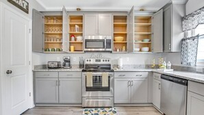 Una cocina moderna con gabinetes grises, un horno de acero inoxidable, un microondas y una cafetera.