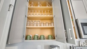 Un armario de cocina con repisas que contienen vasos y tazas.