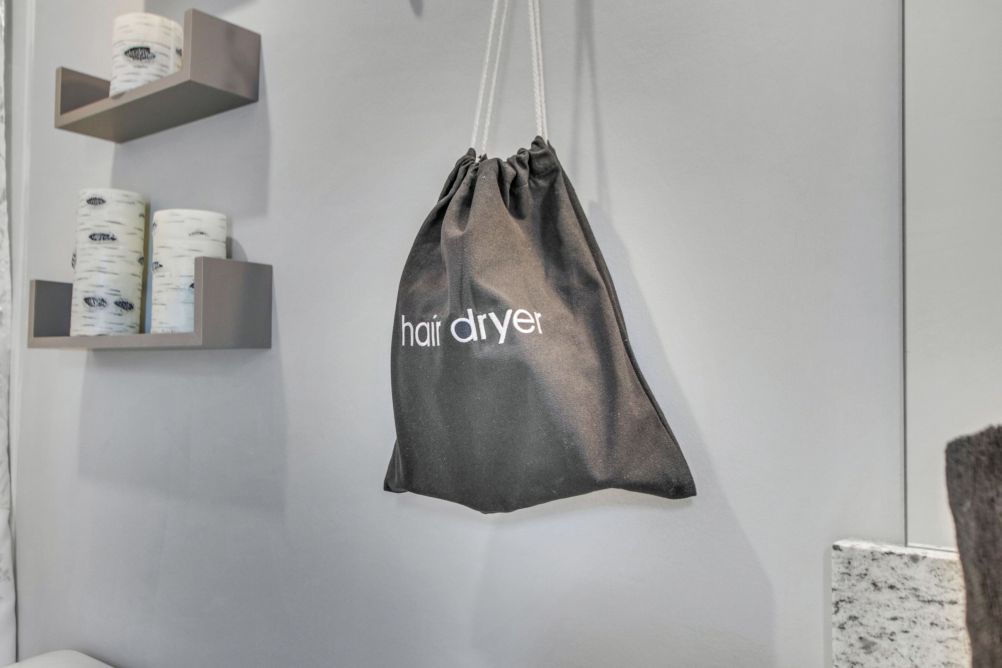 A hair dryer bag hanging on a wall in a bathroom.